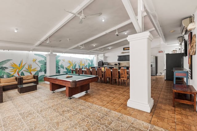 The pavilion: lounge seating, a pool table and a long dining table, with the kitchen at the back